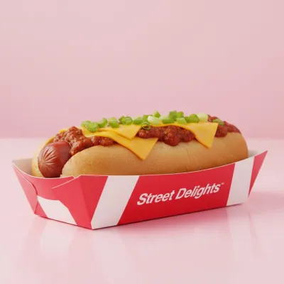 Printed red and white corn dog tray holding a cheese-topped corn dog