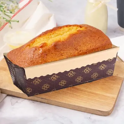Cake baked in a printed pleated paper loaf case on a wooden board