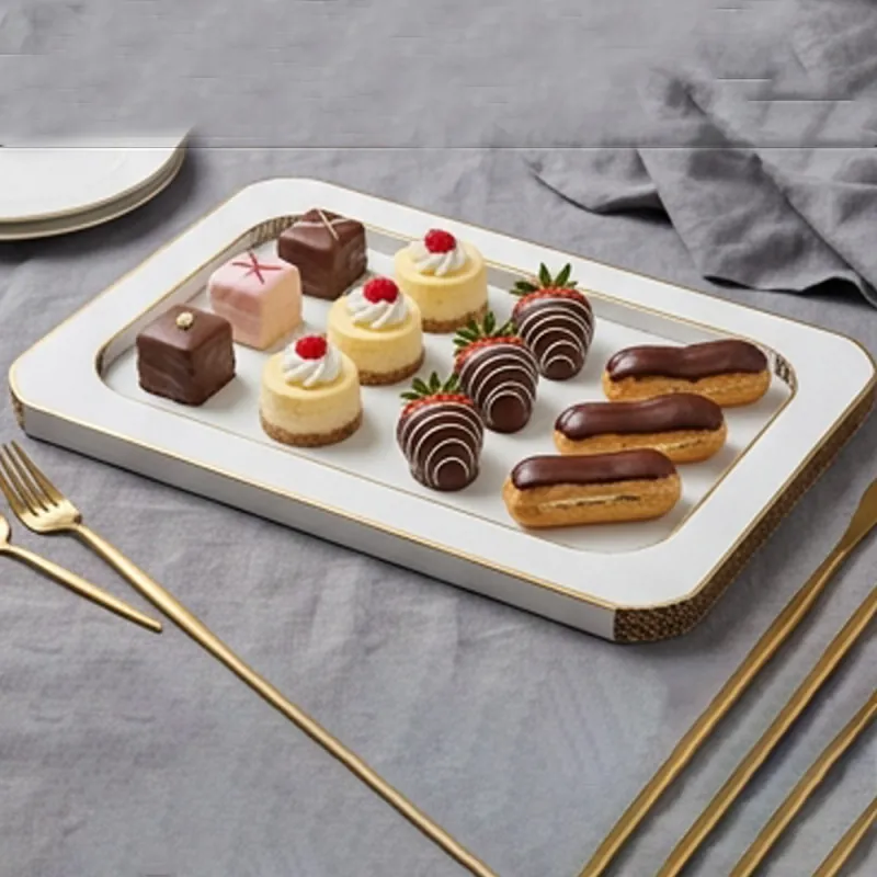 White dessert platter with a raised rim holding eclairs and chocolate desserts