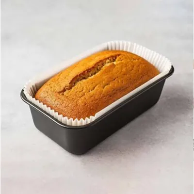 Baked loaf cake in a paper liner inside a black loaf tin