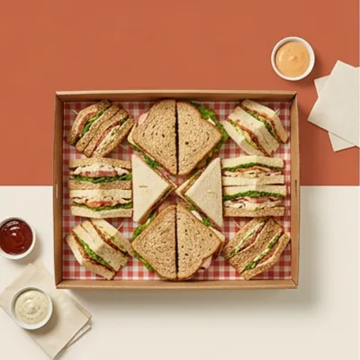 Sandwich platter with a checked liner holding sandwich triangles and dip pots