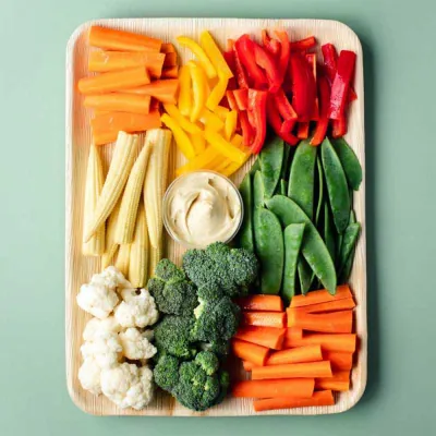 Crudité platter arranged with carrot, pepper and celery sticks around a central hummus well