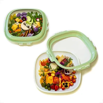 Square crudité trays with green fitted lids holding vegetable and grain salads