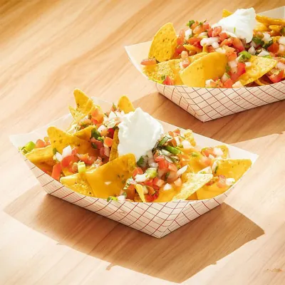 Two printed food trays holding loaded nachos with sour cream and salsa