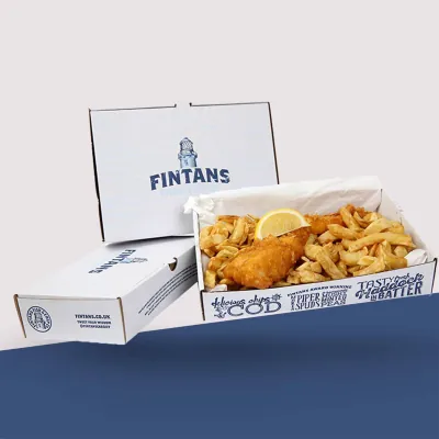 Two printed fish and chips boxes stacked, one holding fried fish and scampi