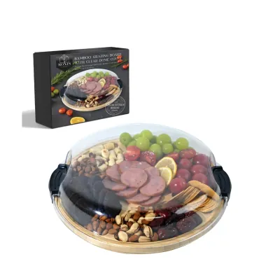 Round grazing board under a clear dome holding cured meats, nuts and grapes