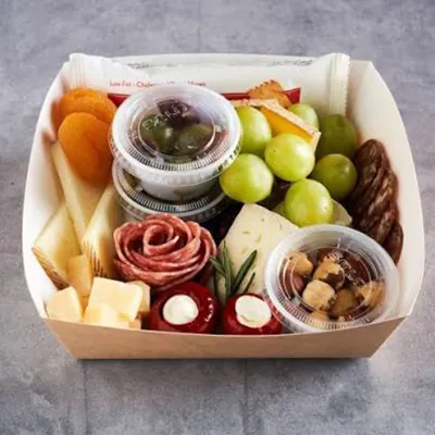 White mini charcuterie tray holding cheese, cured meat, grapes and dip pots