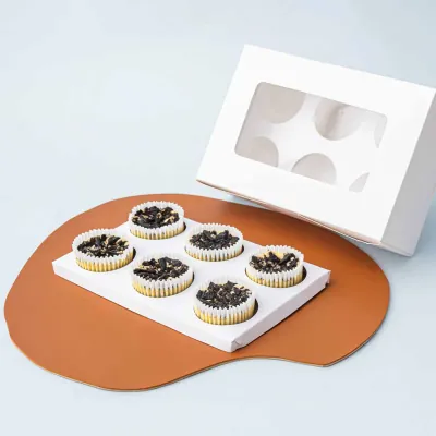 White cupcake insert with six wells beside decorated cupcakes