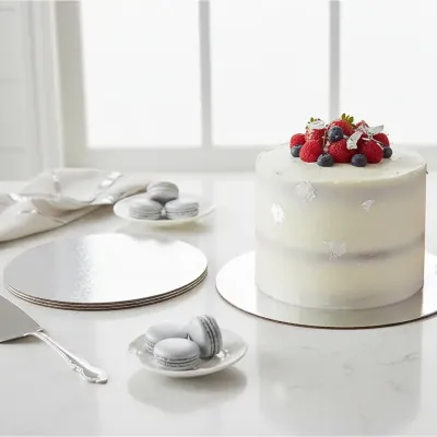 Naked celebration cake on a white round cake board with serving plates