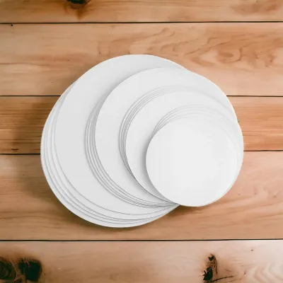 Stack of white round cake boards in several diameters on a wooden surface