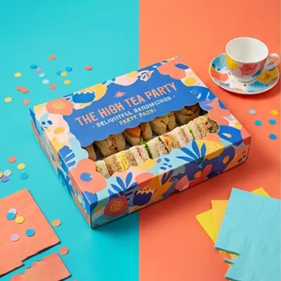 Brightly patterned high tea sandwich box with a window showing filled sandwiches