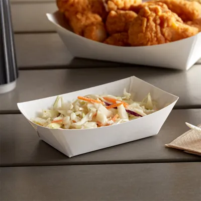 White paper food trays holding fried chicken and coleslaw on an outdoor table